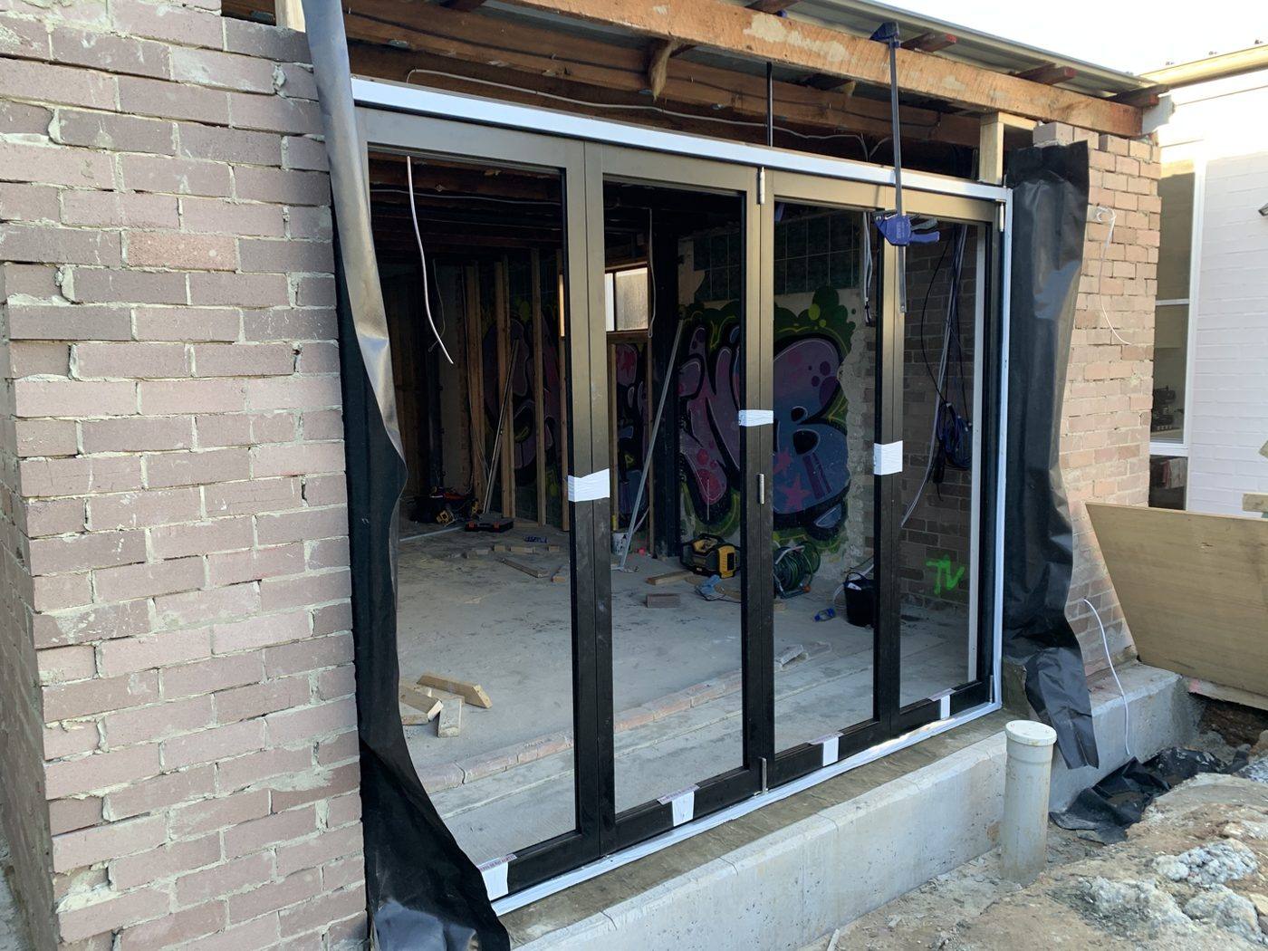 Black aluminium bi-fold door frame in the new rear opening, Dulwich Hill by Loel Homes