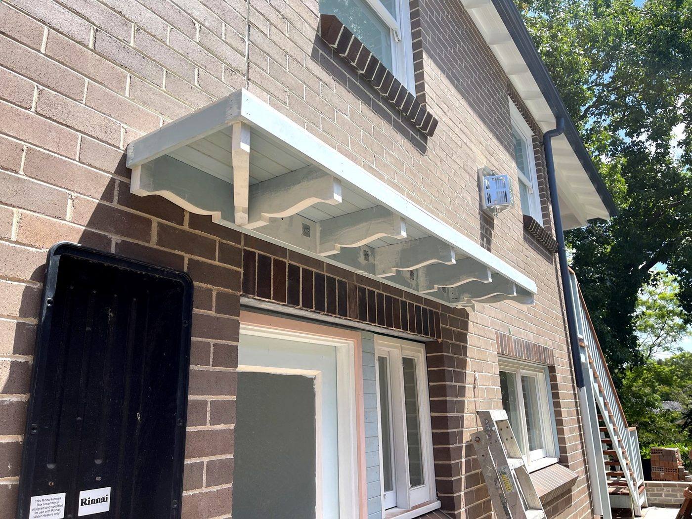 Decorative timber window awning hood lined underneath and top-coated white with painted corbels on a brick Eastwood home by Loel Homes