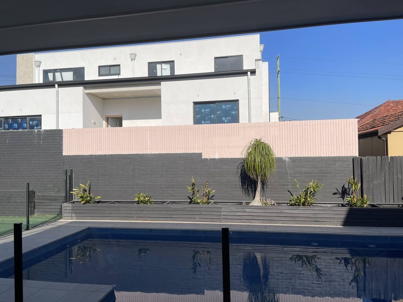 Pool with rendered feature wall and black metal fencing, finished by Loel Homes