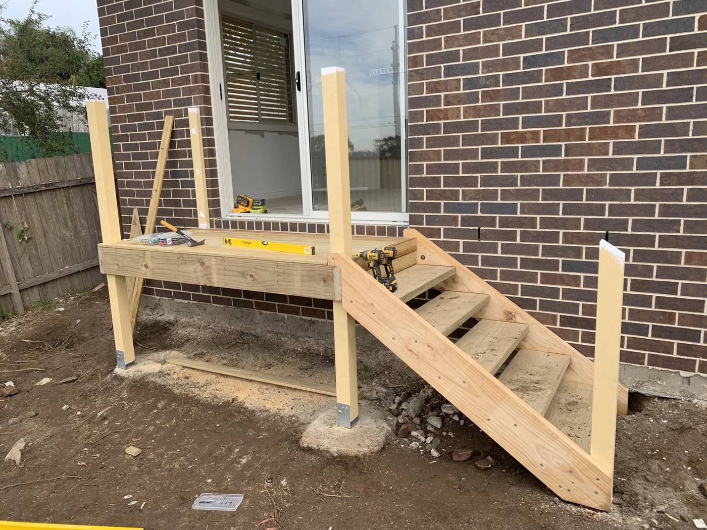 Timber deck subframe and stair stringers being framed against the brick wall by Loel Homes