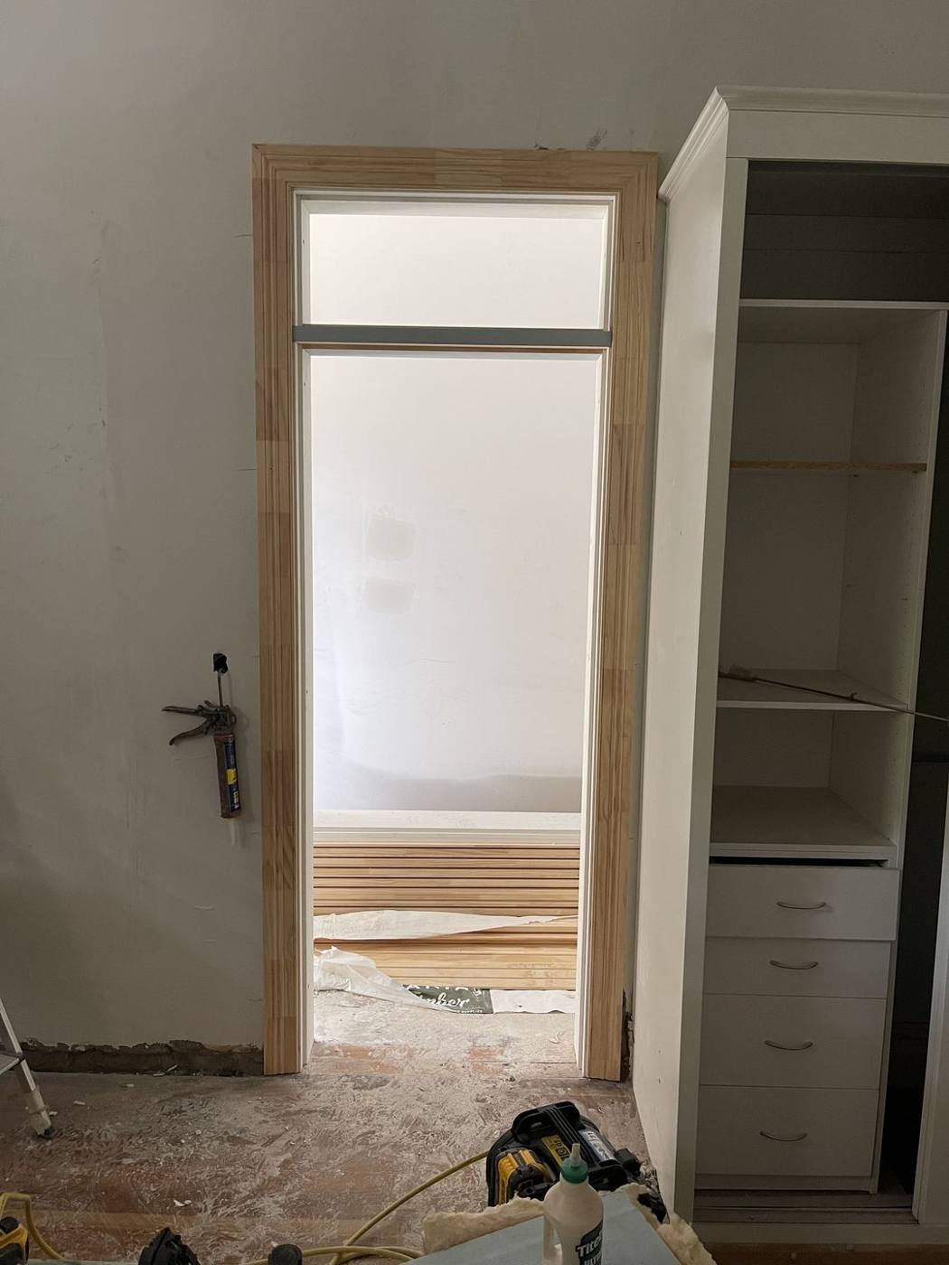 Fanlight door beside a built-in wardrobe with drawers and shelving, heritage terrace joinery by Loel Homes